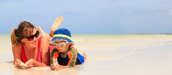 Mãe e filho se divertindo com água na praia — Fotografia de Stock