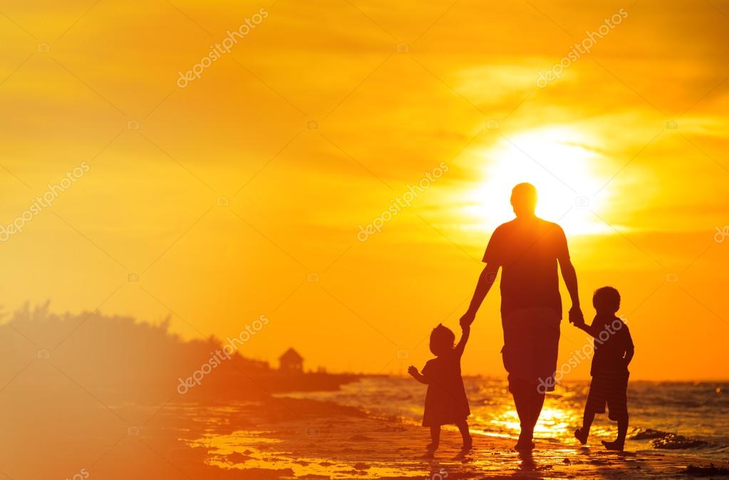 Padre y dos hijos caminando al atardecer: fotografía de stock
