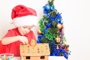gingerbread ev inşa Santas şapkalı küçük çocuk