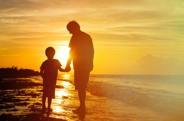 Sylwetki ojca i syna, trzymając się za ręce na zachodzie słońca — Zdjęcie stockowe