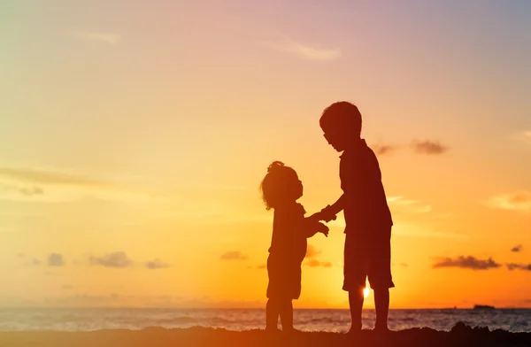 Mały chłopiec i dziewczynka trzymając się za ręce na zachodzie słońca — Zdjęcie stockowe
