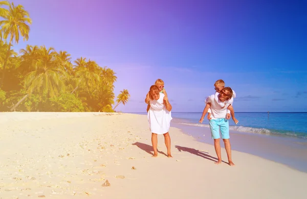 Familia joven con dos niños caminando en la playa — Foto de Stock