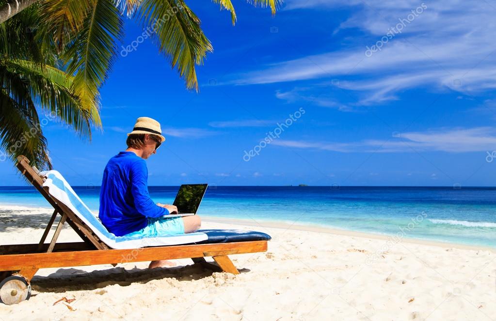 man with laptop on tropical beach