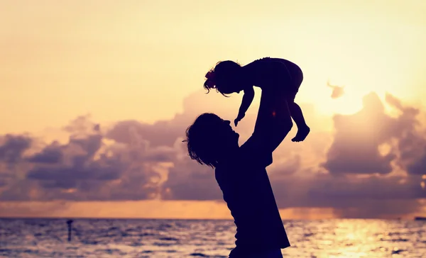 Pai e pequena filha silhuetas ao pôr do sol — Fotografia de Stock