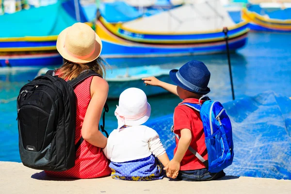 Mor och två barn tittar på traditionella båtar i malta — Stockfoto