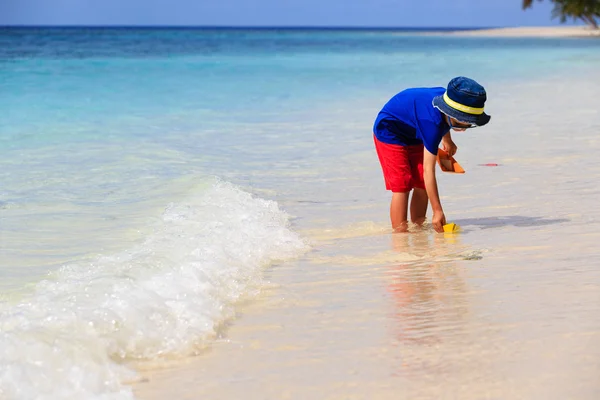 Kleine jongen spelen met papier boot op strand — Stockfoto