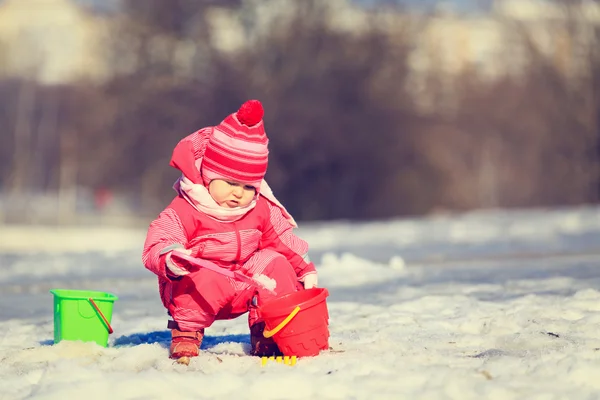 Маленькая девочка зимой копает снег — стоковое фото