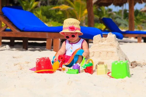Nettes kleines Mädchen spielt mit Sand am Strand — Stockfoto