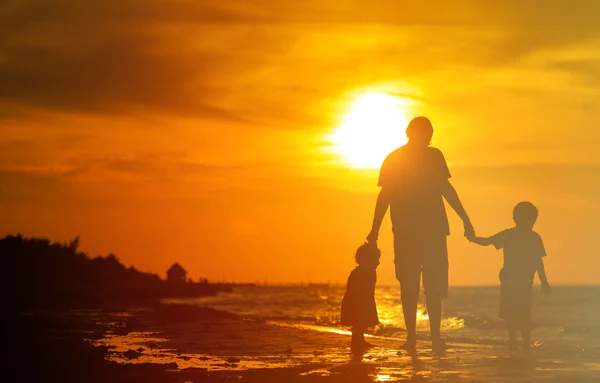 Padre y dos hijos caminando al atardecer — Foto de Stock