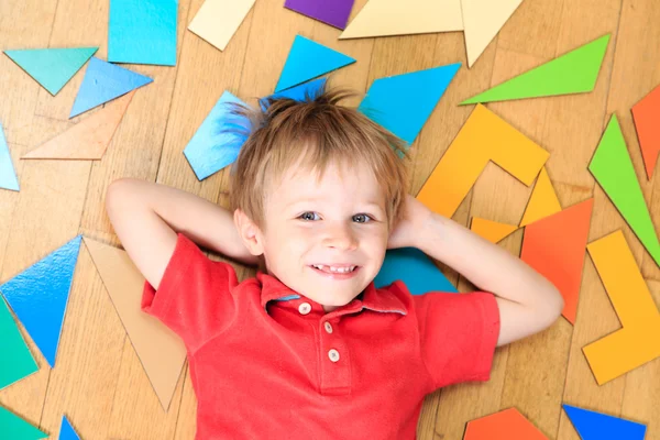 Happy little boy with puzzle toys on wooden floor — Stock Photo, Image