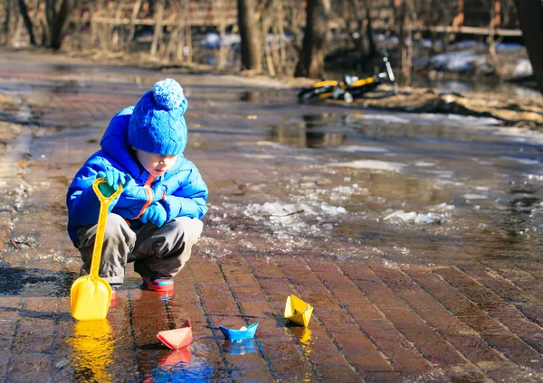 Child playing with paper boats in spring water — Stock Photo, Image