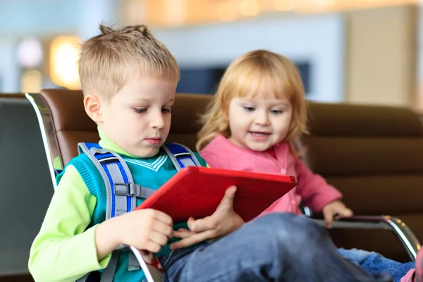 Kids looking at touch pad while waiting in the airport — Stock Photo, Image