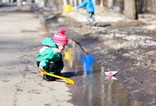 Ребенок играет с бумажными лодками в родниковой воде — стоковое фото