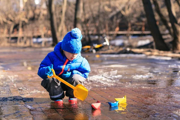 Ребенок играет с бумажными лодками в родниковой воде — стоковое фото