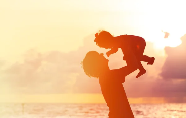 Vader en kleine dochter silhouetten bij zonsondergang — Stockfoto