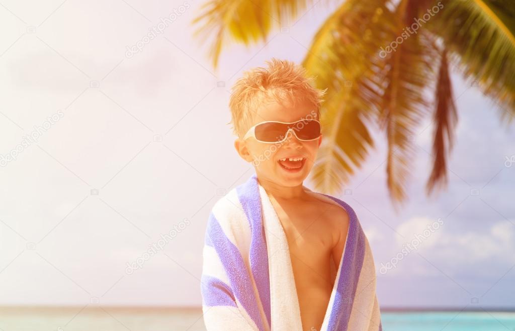 happy little boy laugh wrapped in beach towel