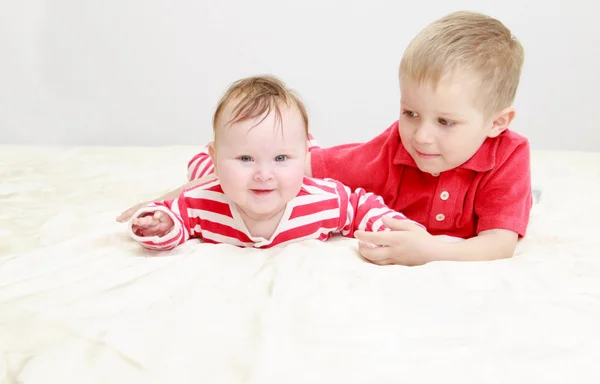 Little brother playing with newborn sister — Stock Photo, Image