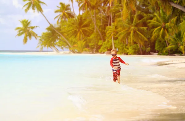 Kleine jongen stromend spatten water op strand — Stockfoto