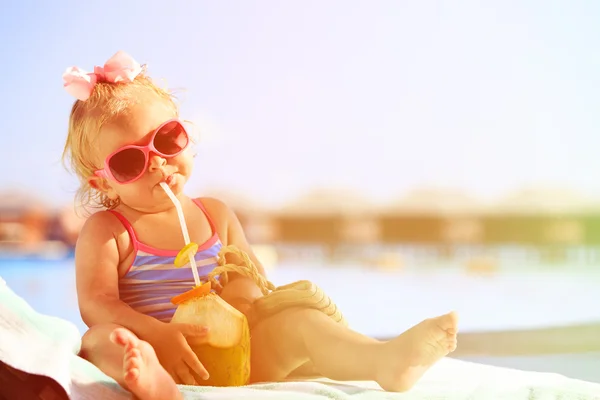 Petite fille boire un cocktail de noix de coco sur la plage — Photo