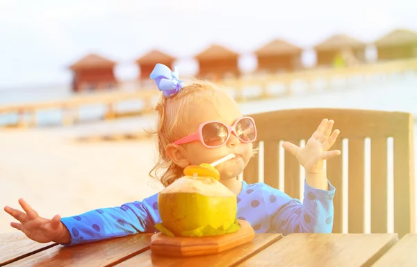 Petite fille boire un cocktail de noix de coco sur la plage — Photo