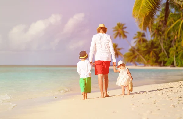 Vader en twee kinderen walking op strand — Stockfoto