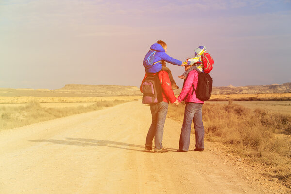 family with two kids on shoulders travel at scenic road