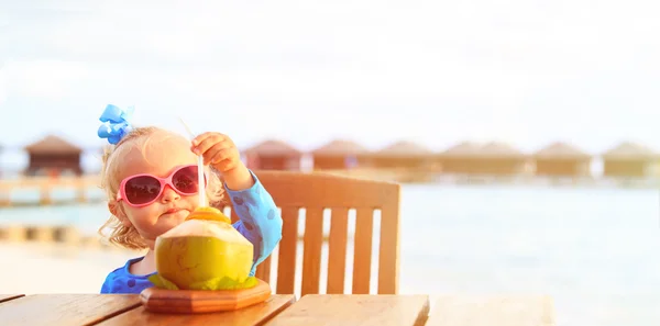 Μικρό κορίτσι πίνοντας κοκτέιλ καρύδας στην παραλία — Φωτογραφία Αρχείου