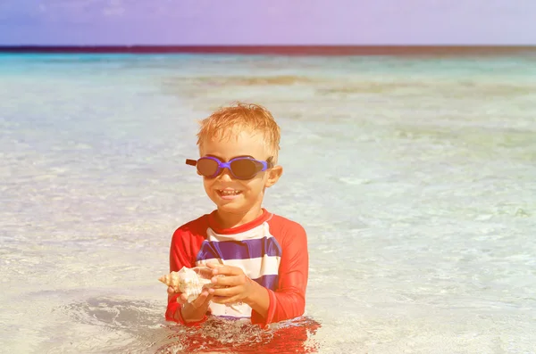 Mały chłopiec pływanie gospodarstwa powłoki na plaży — Zdjęcie stockowe