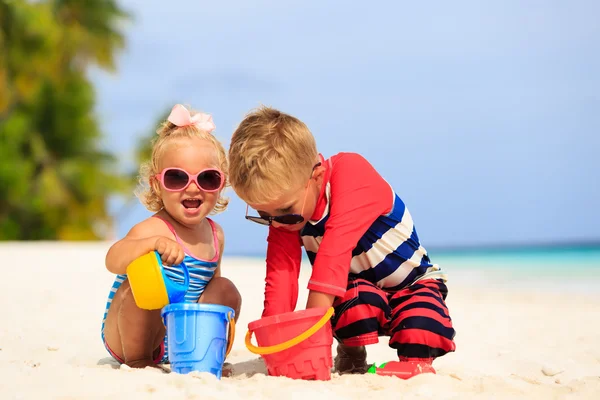 可爱小男孩和蹒跚学步的女孩玩沙滩上的沙子 — 图库照片