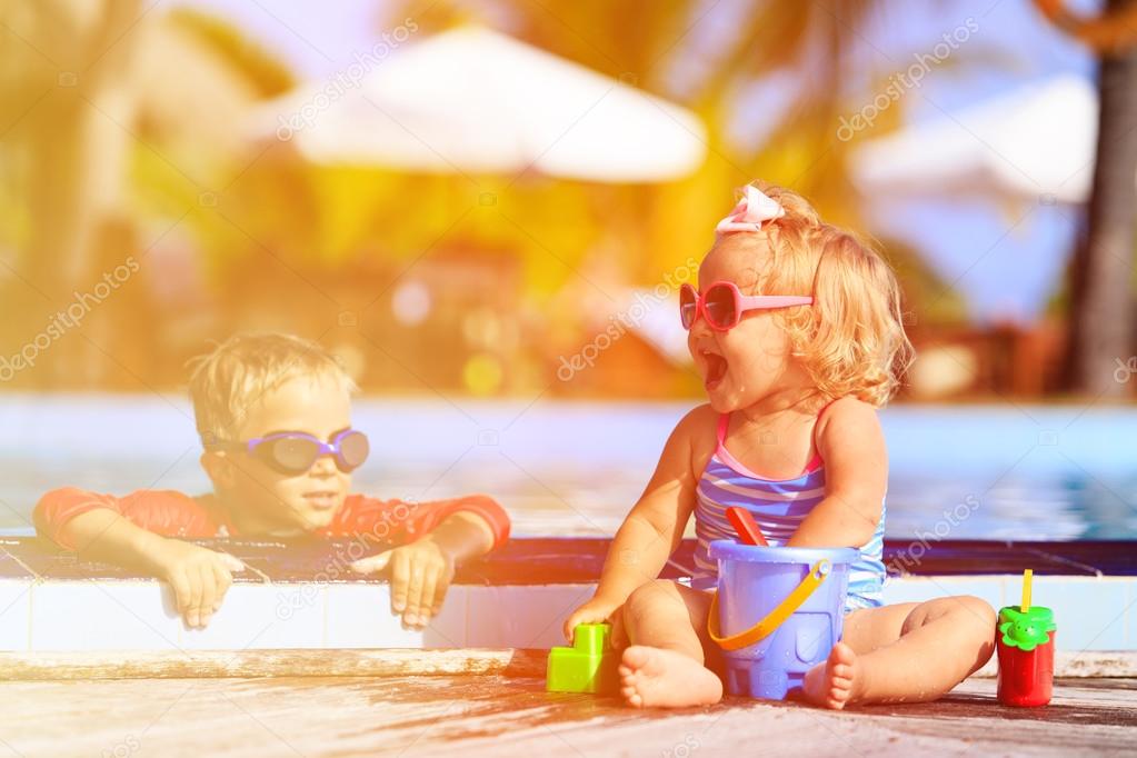 little boy and girl playing in swimming pool at beach