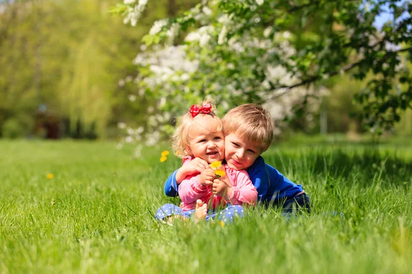 Crianças felizes brincam com flores da primavera — Fotografia de Stock