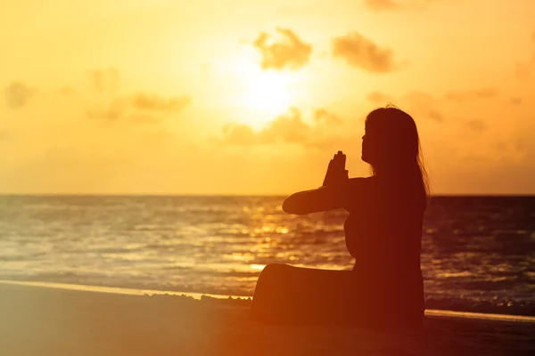 Nuori nainen joogaa auringonlaskun rannalla — kuvapankkivalokuva
