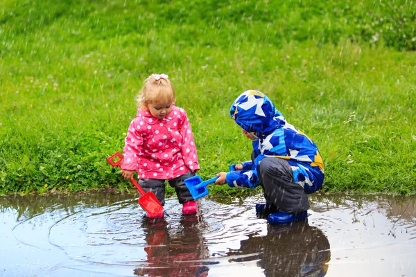 Маленький мальчик и девочка веселятся под дождем — стоковое фото