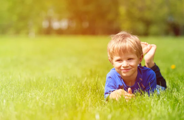 봄에 푸른 잔디에 누워 귀여운 행복 한 소년 — 스톡 사진