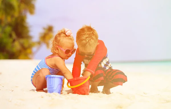 Cute little boy and toddler girl play on beach — Stock Photo, Image