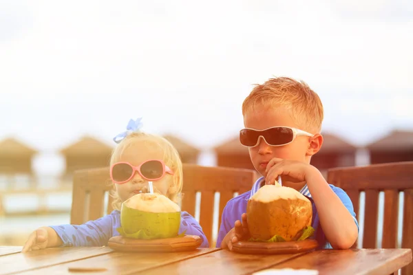 Little boy and toddler girl drinking coconut cocktail on beach — Stock Photo, Image