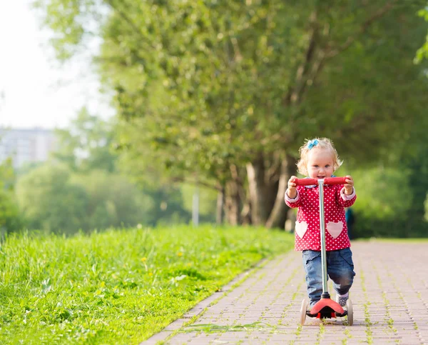 Linda niña montando scooter en el parque de verano — Foto de Stock