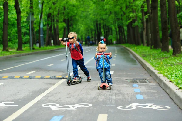 Niedliche kleine Junge und Kleinkind Mädchen Roller fahren — Stockfoto