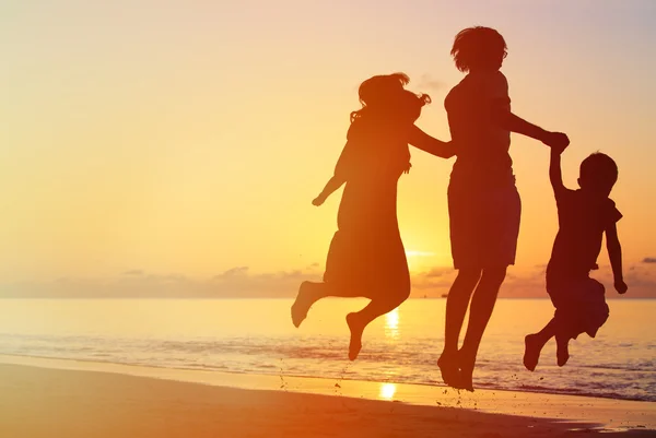 Família feliz com dois filhos pulando ao pôr do sol — Fotografia de Stock