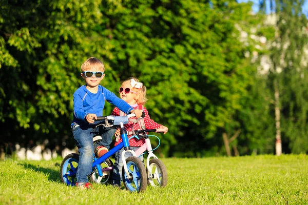 小男孩和蹒跚学步女孩骑自行车中夏公园 — 图库照片