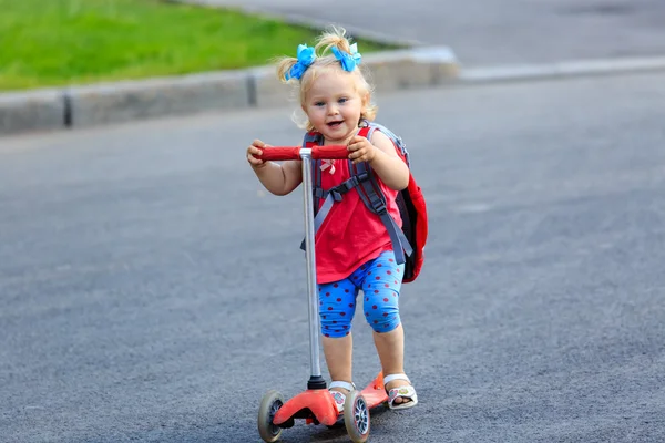 Carino piccolo bambino ragazza equitazione scooter in città — Foto Stock