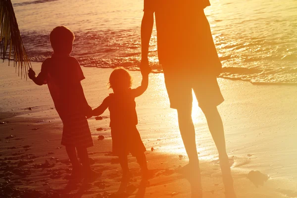 Silhouette de père et deux enfants marchant au coucher du soleil — Photo