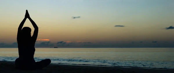 Jovem fazendo ioga na praia do pôr do sol — Fotografia de Stock