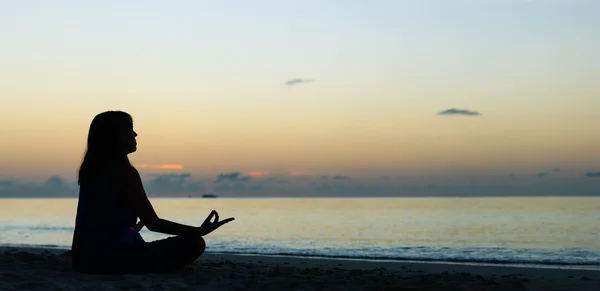 Jonge vrouw doet yoga op zonsondergang strand — Stockfoto