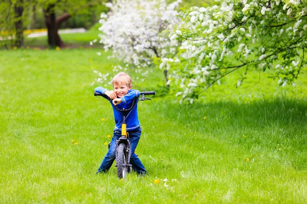 春の庭で自転車に乗る少年 — ストック写真