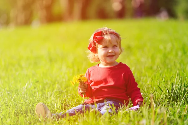 Happy little girl with flowers on green grass Royalty Free Stock Photos