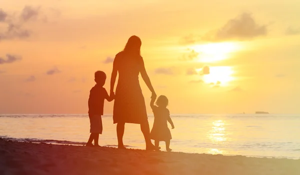 Ibu dan dua anak berjalan di pantai saat matahari terbenam — Stok Foto