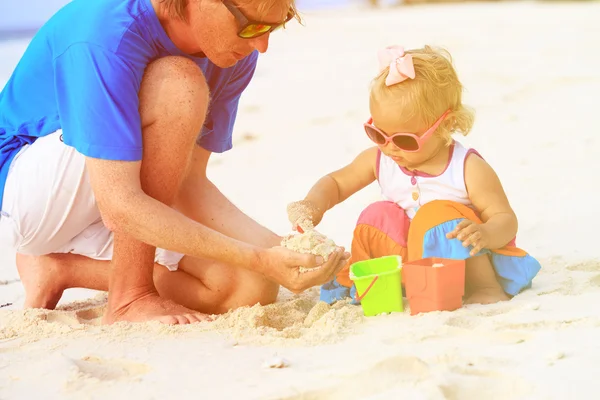 Padre e hija pequeña jugando con arena en la playa — Foto de Stock