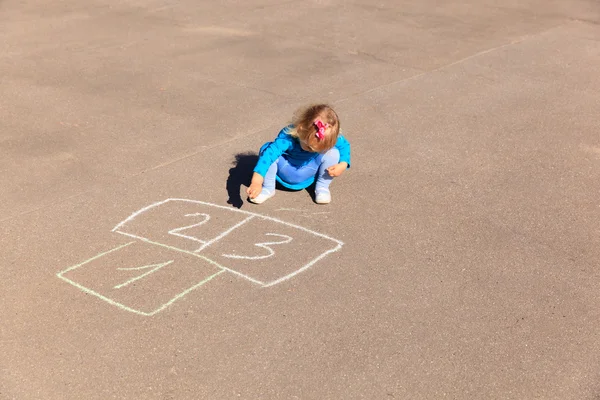 Kleines Mädchen spielt Hopscotch auf Spielplatz — Stockfoto