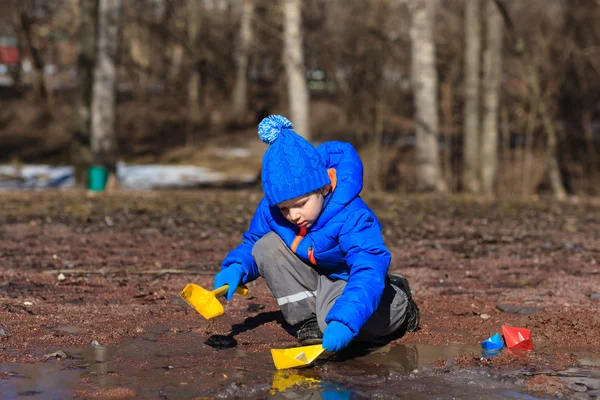 Niño jugando con barcos de papel en primavera — Foto de Stock